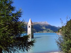 Der herausragende Kirchturm von Graun am Reschensee im Vinschgau als Wahrzeichen der Ferienregion Reschen